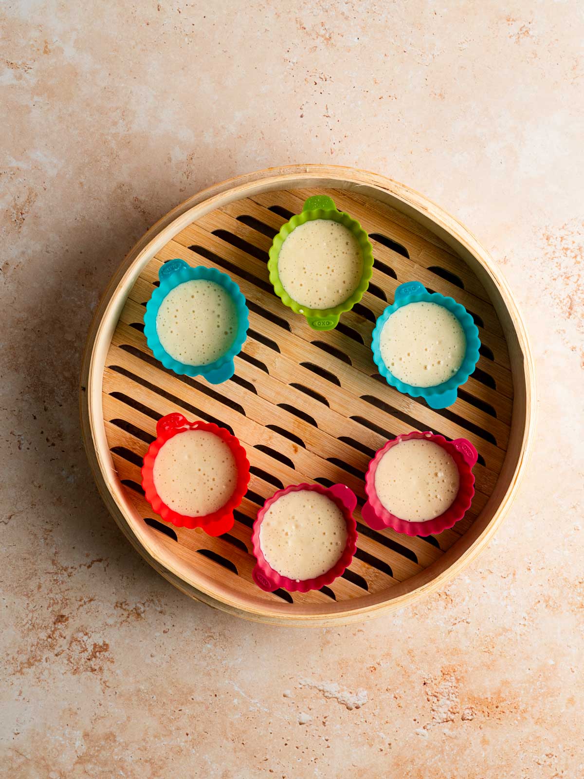 Batter distributed into silicone molds and placed into a bamboo steamer.