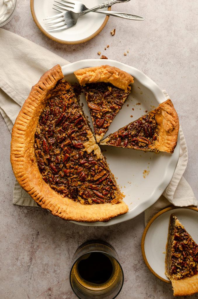 Top view of a vegan maple bourbon pecan pie. Left half is untouched and right half are two slices of pie.