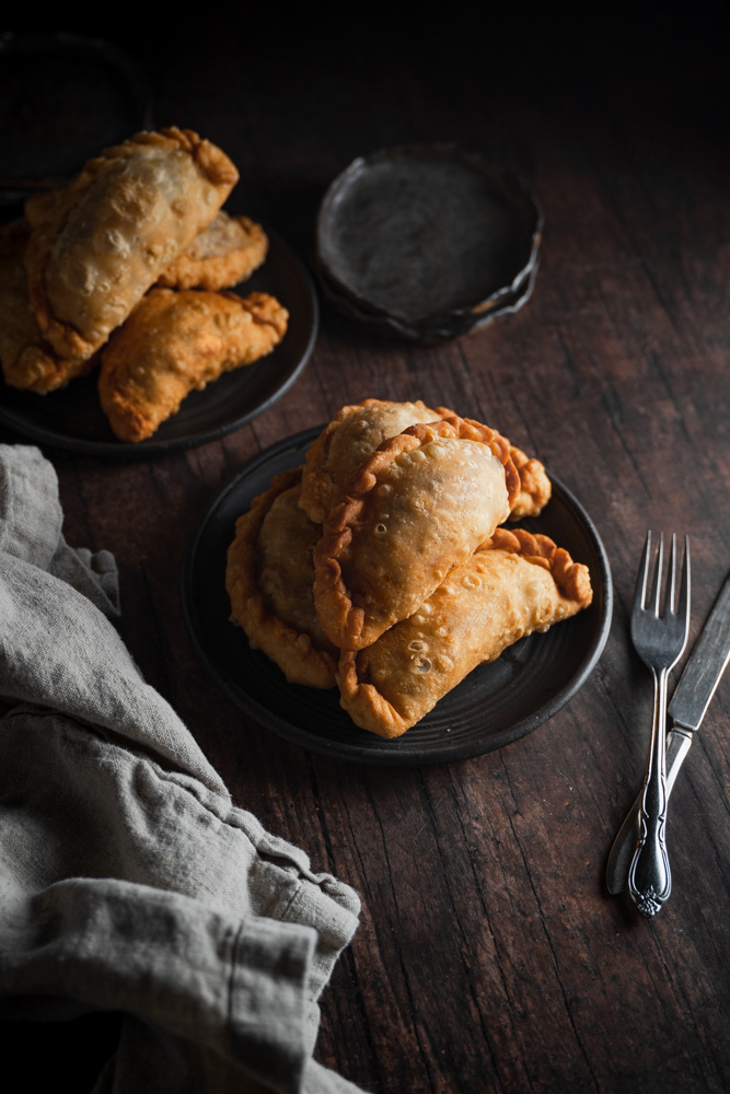45 degree angle of 2 plates filled with empanadas.