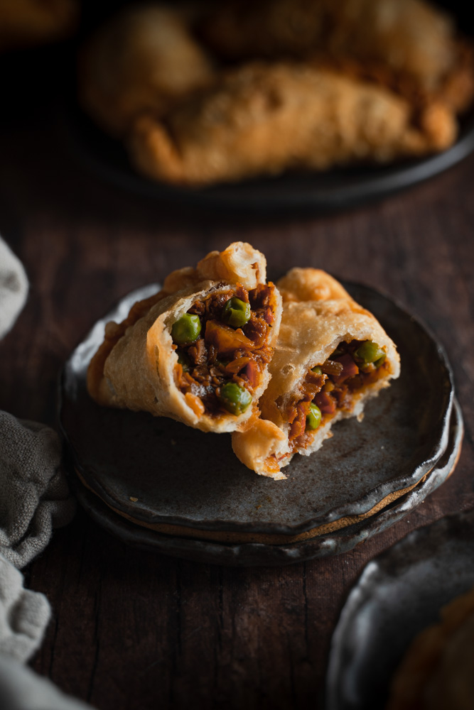 45 degree angle, close up of a filipino empanada open, showing the filling. Plate of empanada blurred in the background 