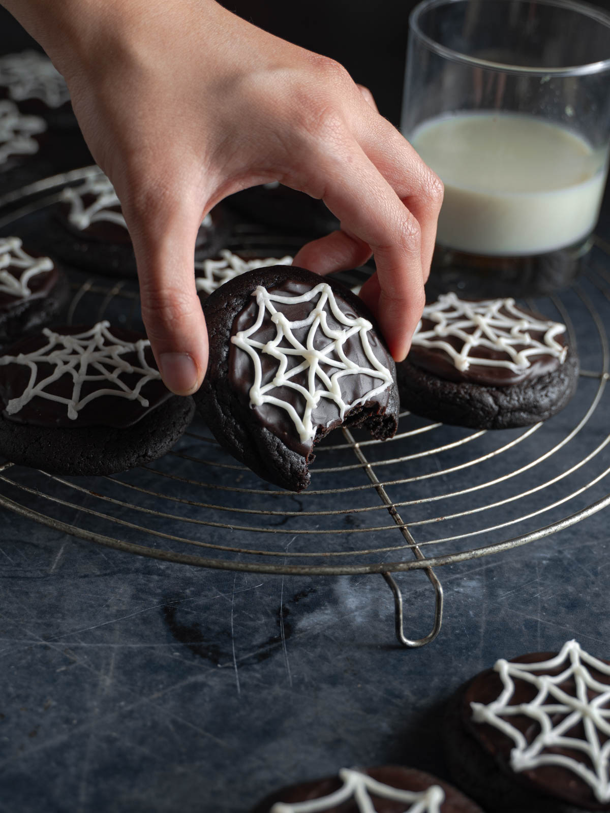 Hand reaching for a bitten vegan halloween spooky cookie.