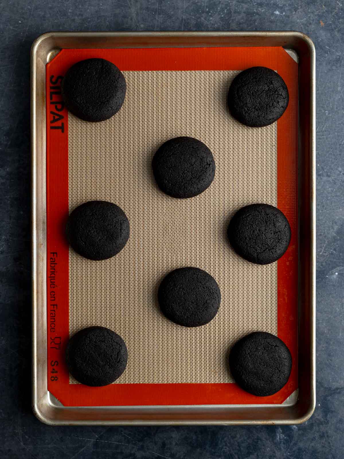 Eight cookies baked on a rimmed baking sheet.