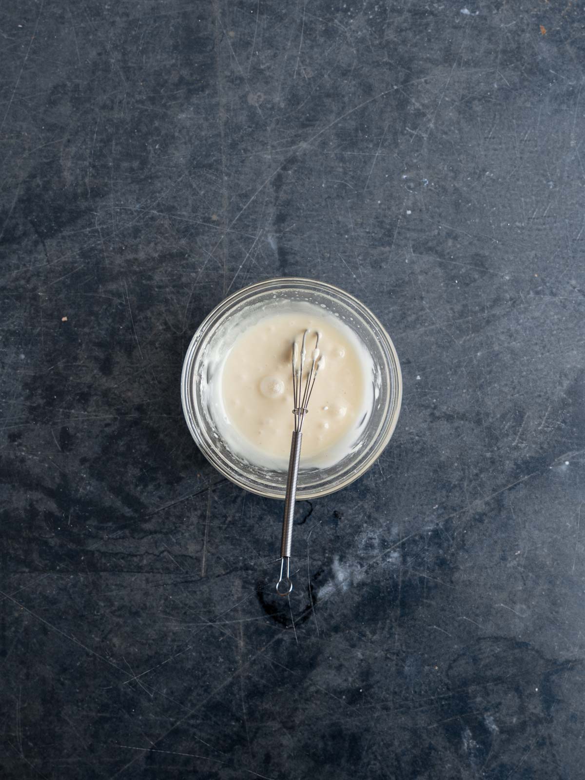 Royal icing mixed in a glass mixing bowl.