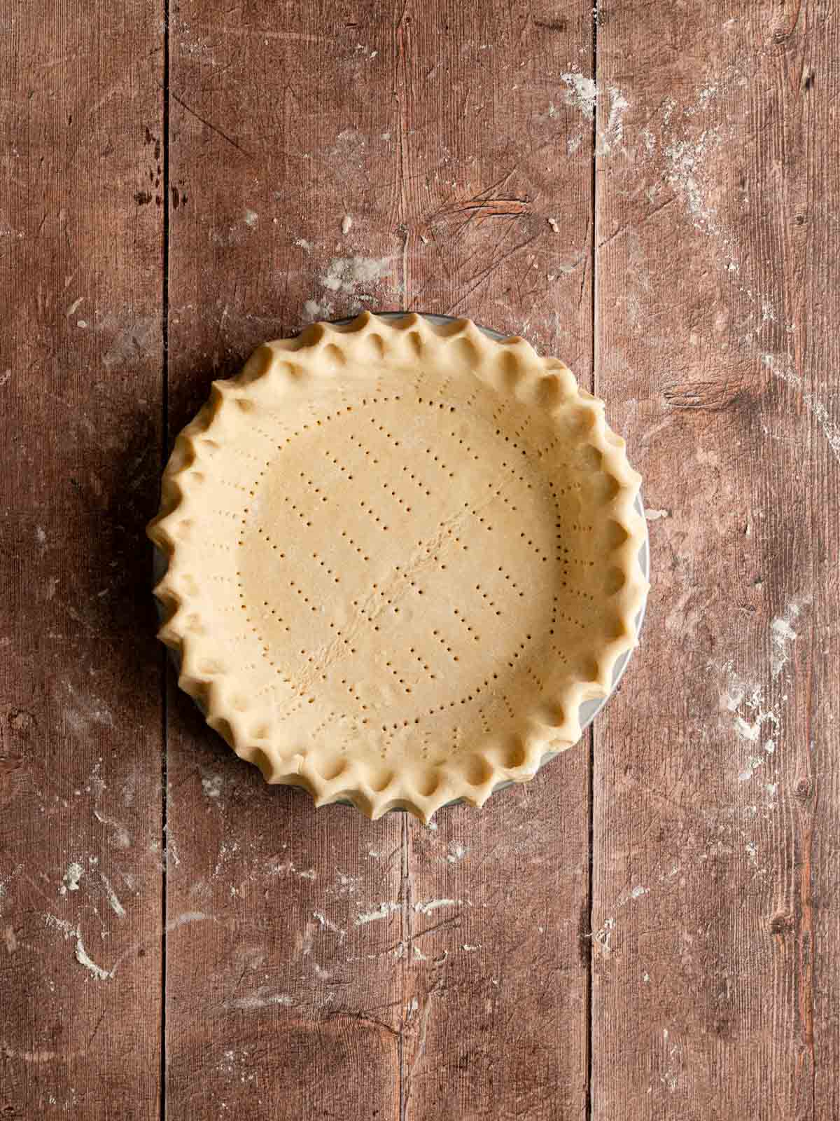 Unbacked vegan pie crust crimped and docked.