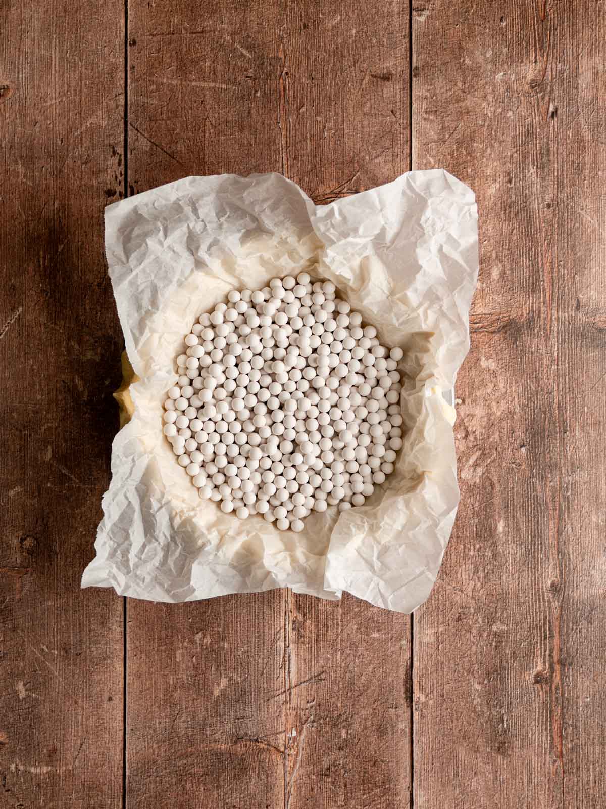 Parchment and pie weights filled into the unbaked vegan pie crust.