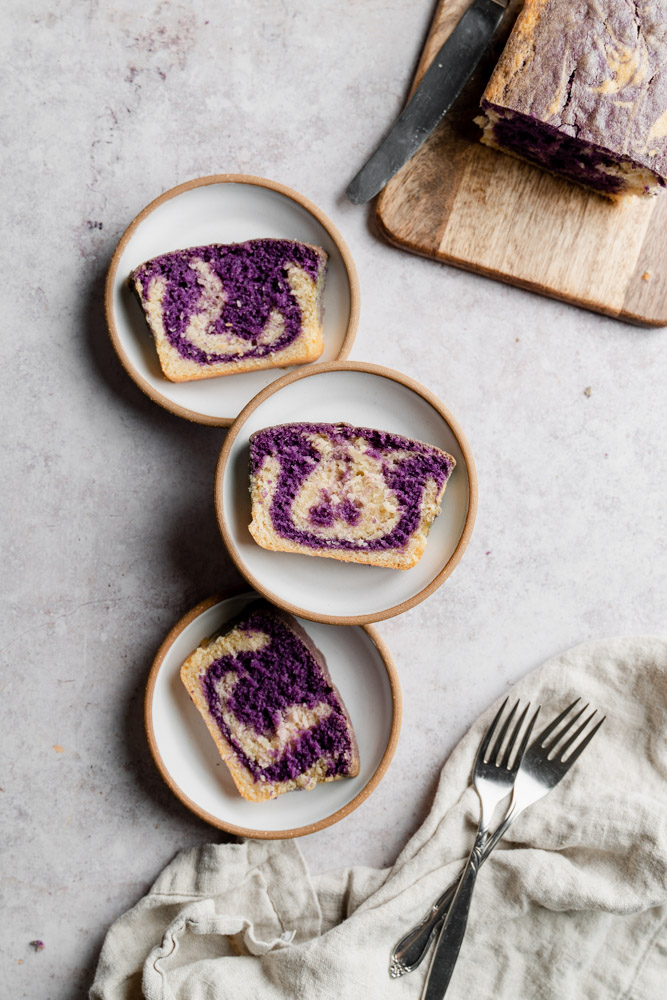 Three slices of vegan ube marble cake distributed among three plates.