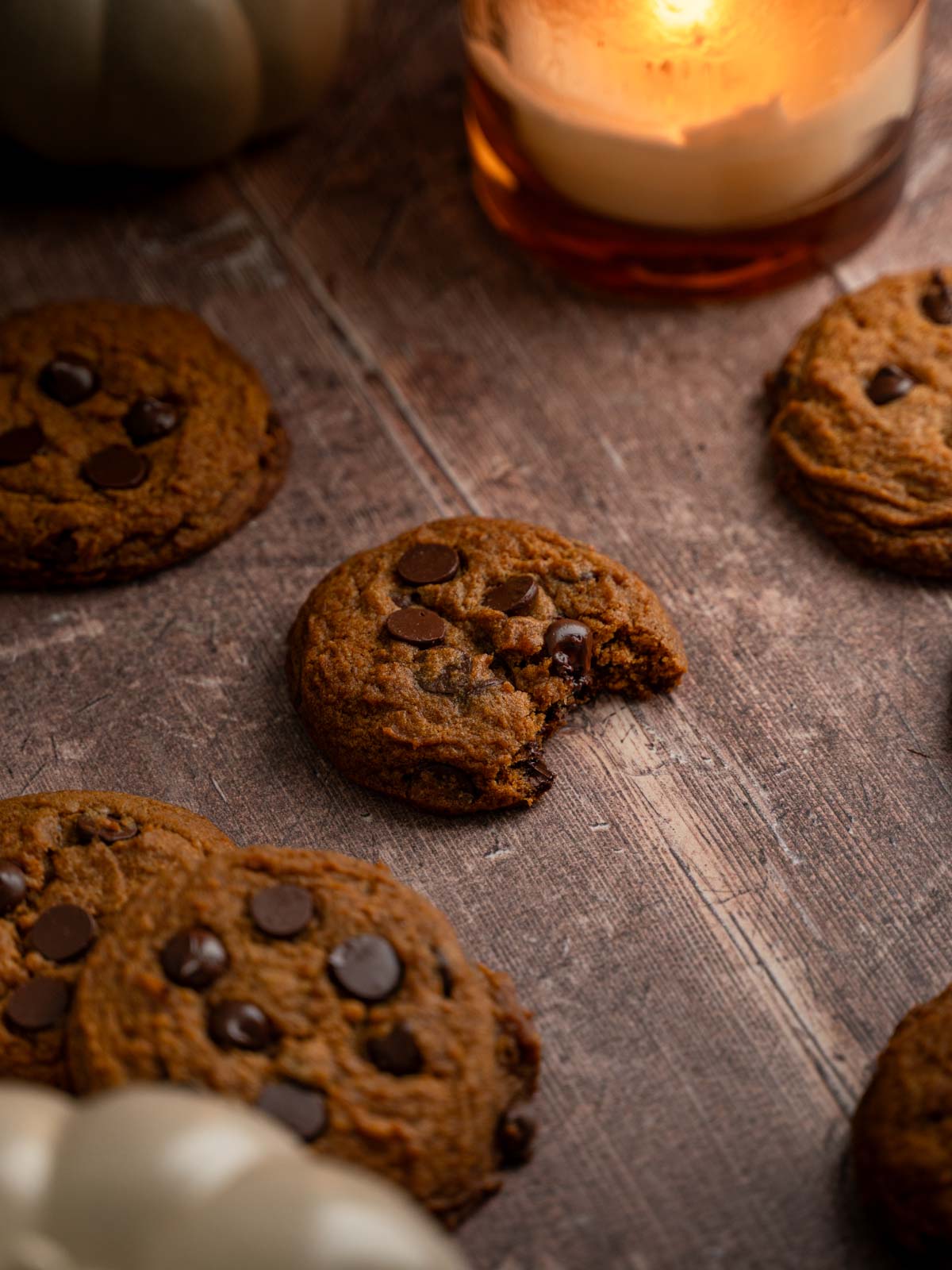 A vegan pumpkin chocolate chip cookie with a bite taken out of it.