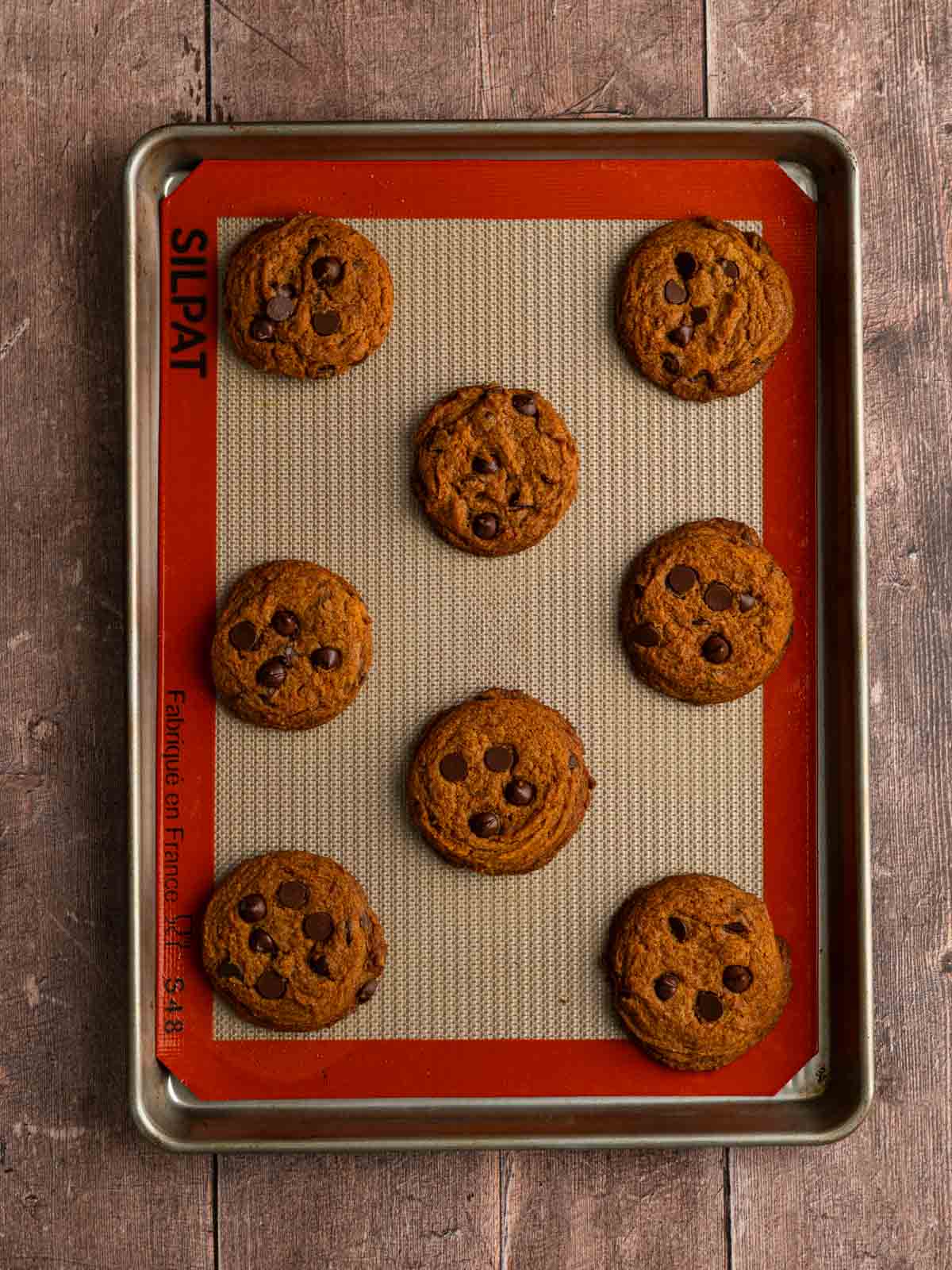 Baked pumpkin chocolate chip cookies on a baking sheet.