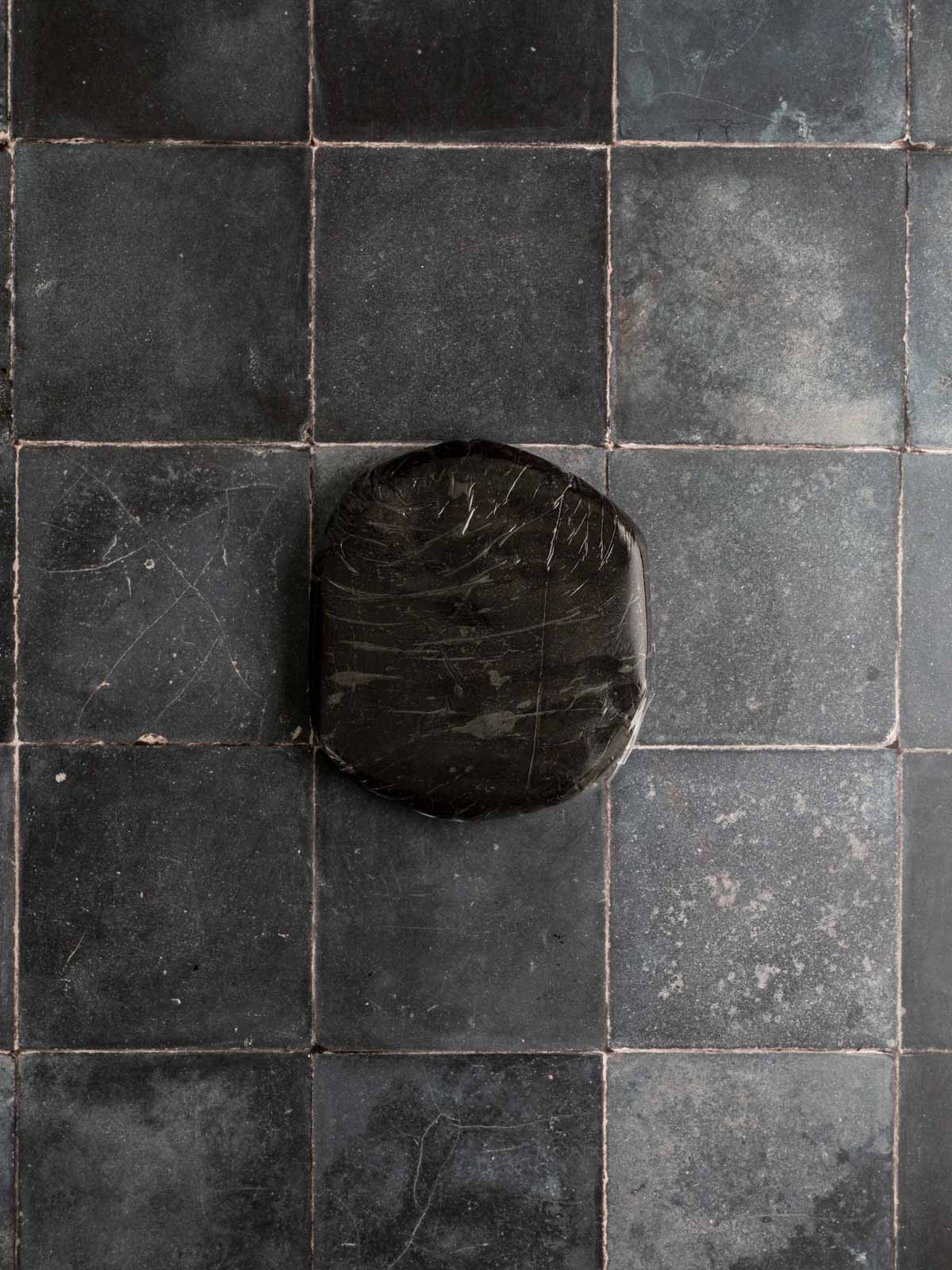 Black cocoa dough kneaded and flattened into a one inch disk and wrapped in food wrap.