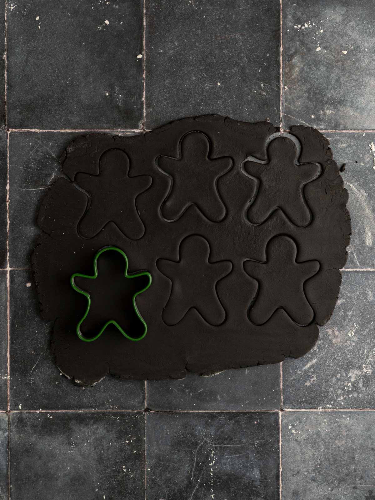 Black cookie dough rolled out and cut out using gingerbread men cookie cutters.