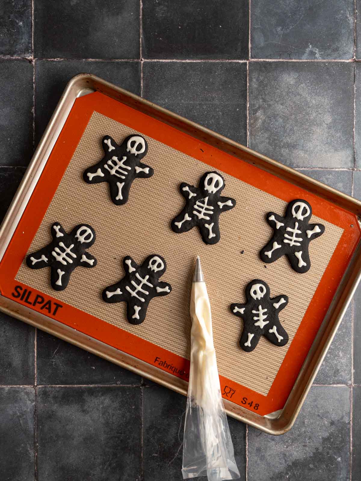 Piped skeleton cookies on a baking sheet.