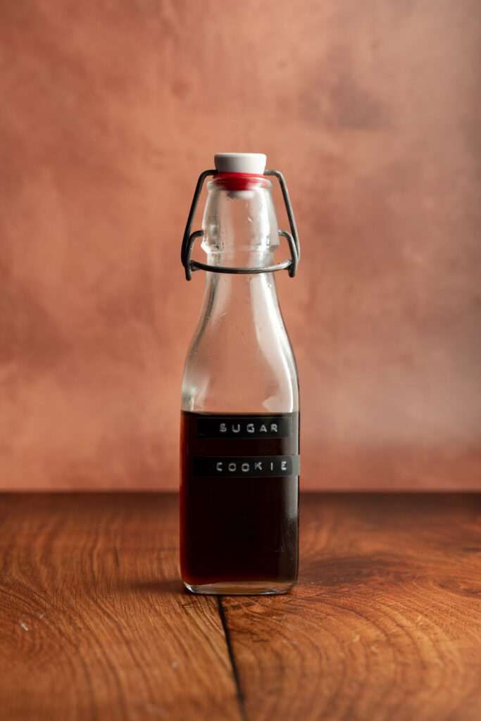 A bottle filled with syrup with a "sugar cookie" label on the front.