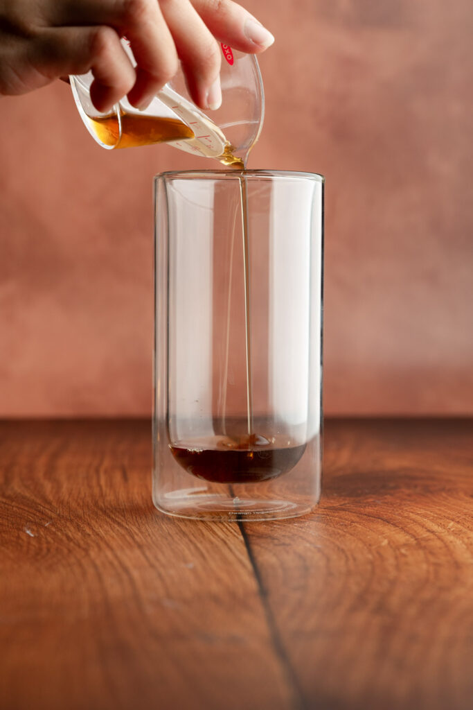 Tall glass with sugar cookie syrup being poured in.
