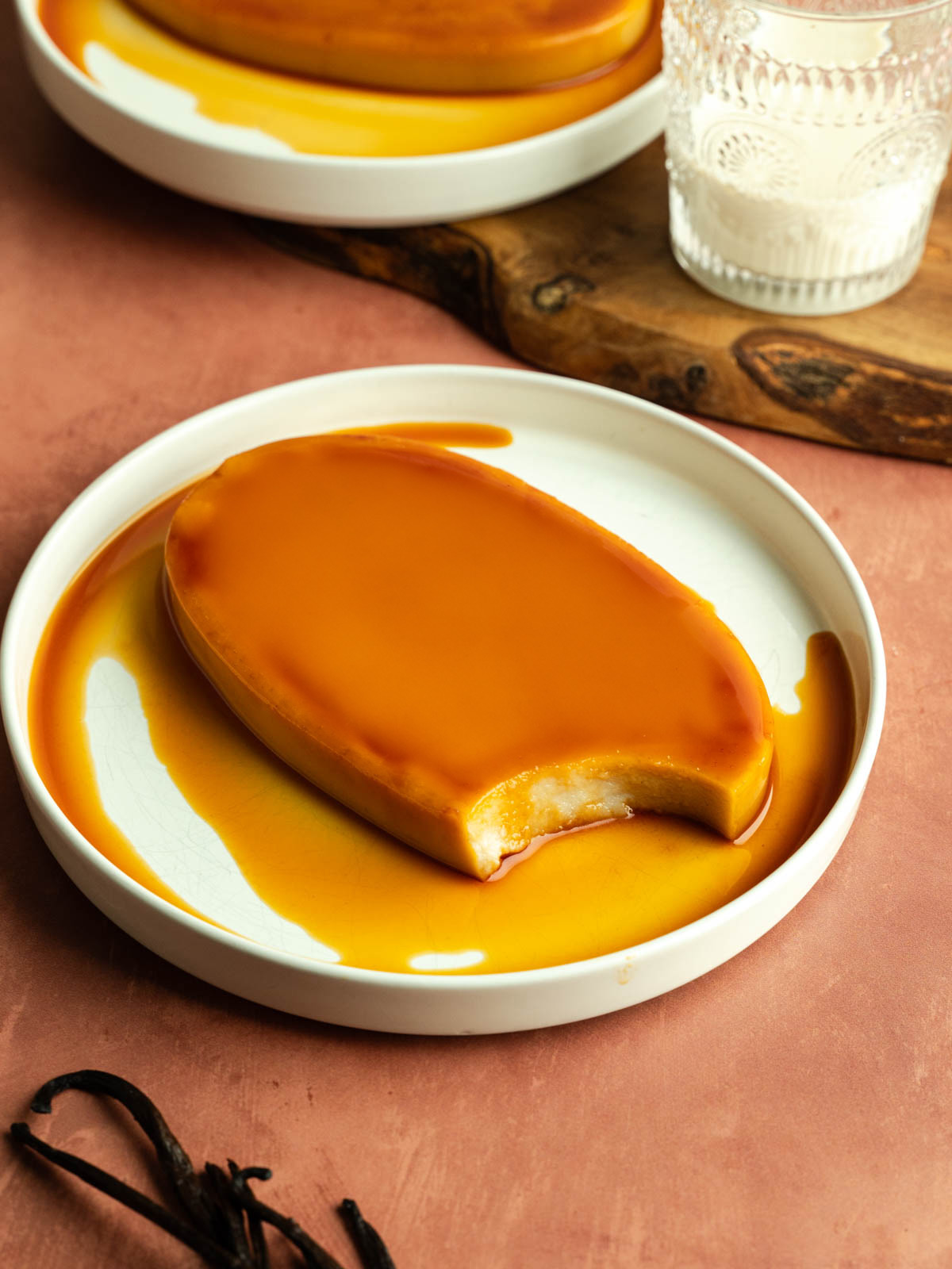 Vegan leche flan on a plate with a spoonful taken out of it.