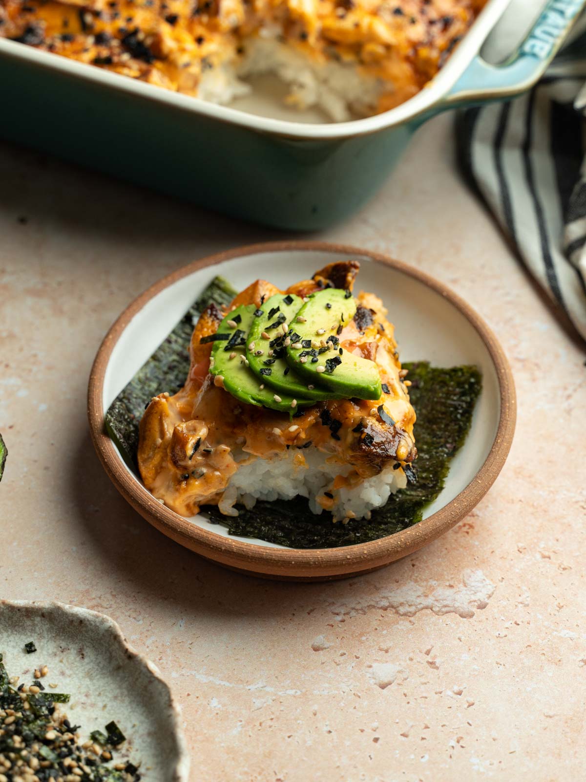 A serving of vegan sushi bake served on over a seaweed snack on a plate.