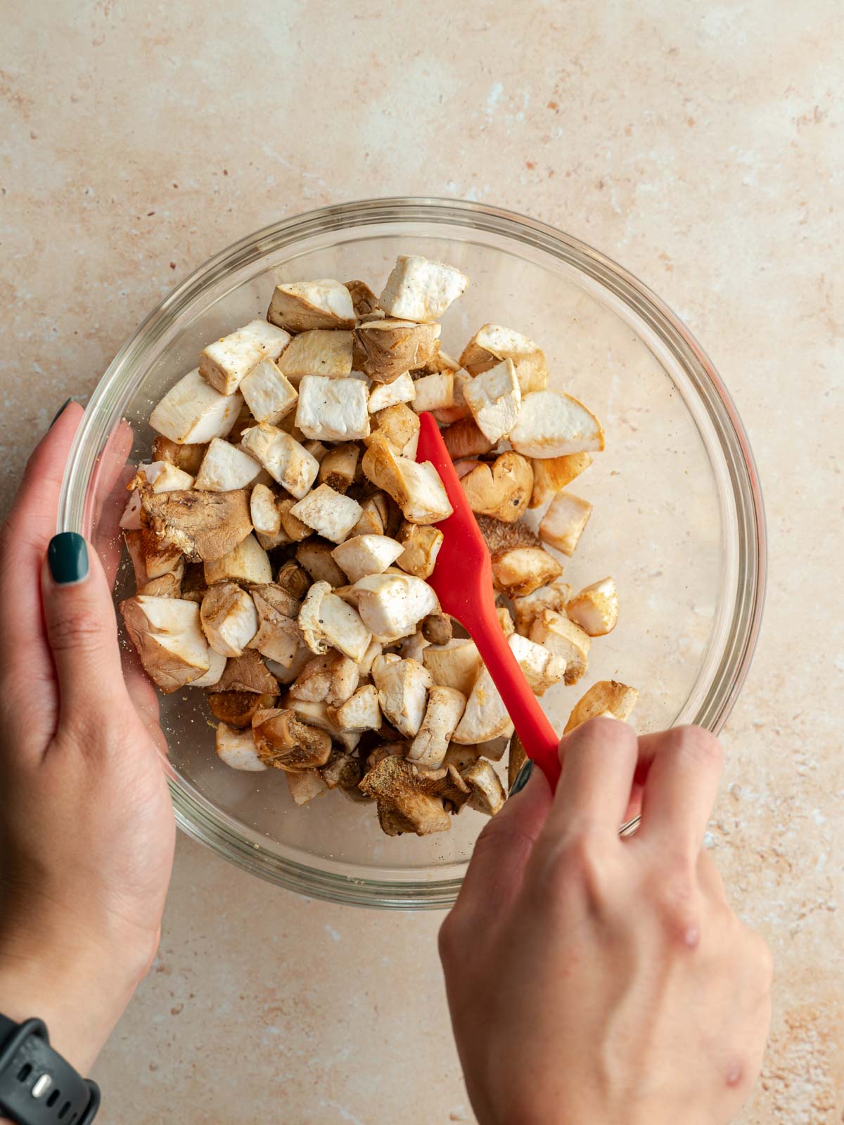 Mixing raw, cubed oyster mushrooms in a bowl with seasoning.