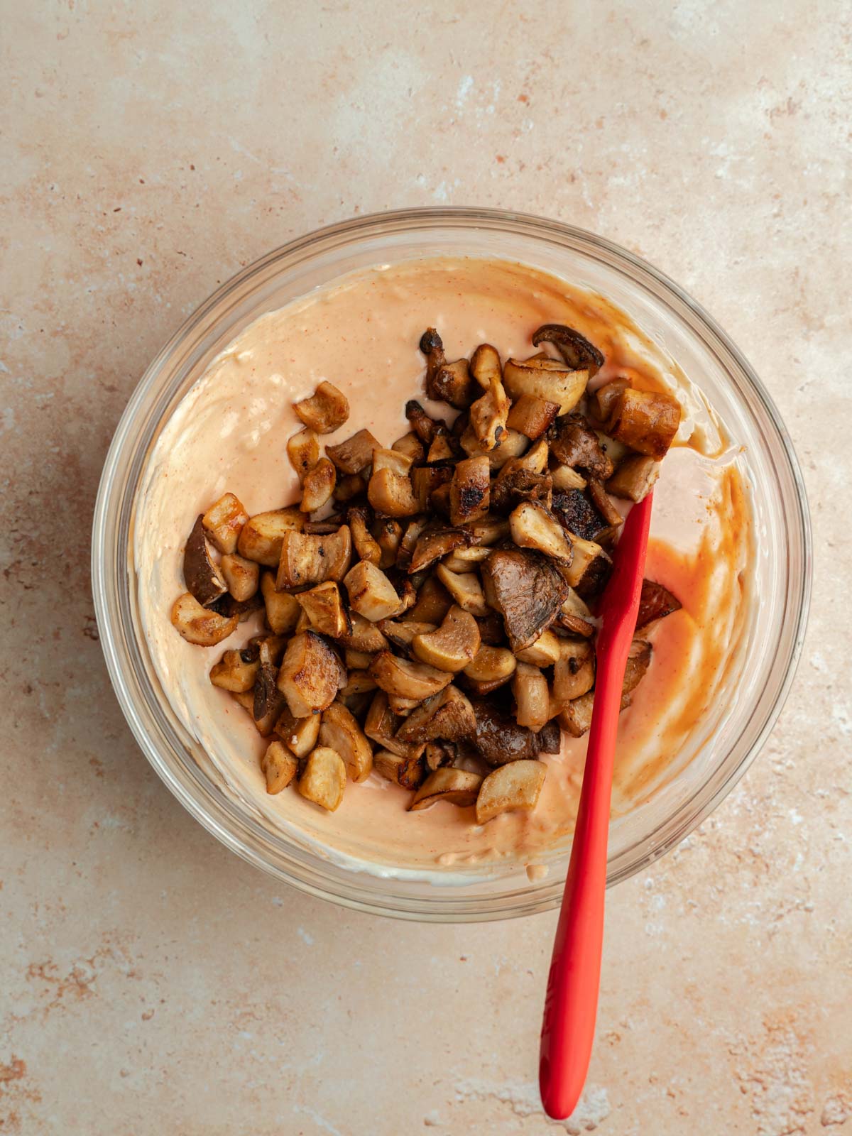 Mixing cooked oyster mushrooms in bowl of sriracha mayonnaise.