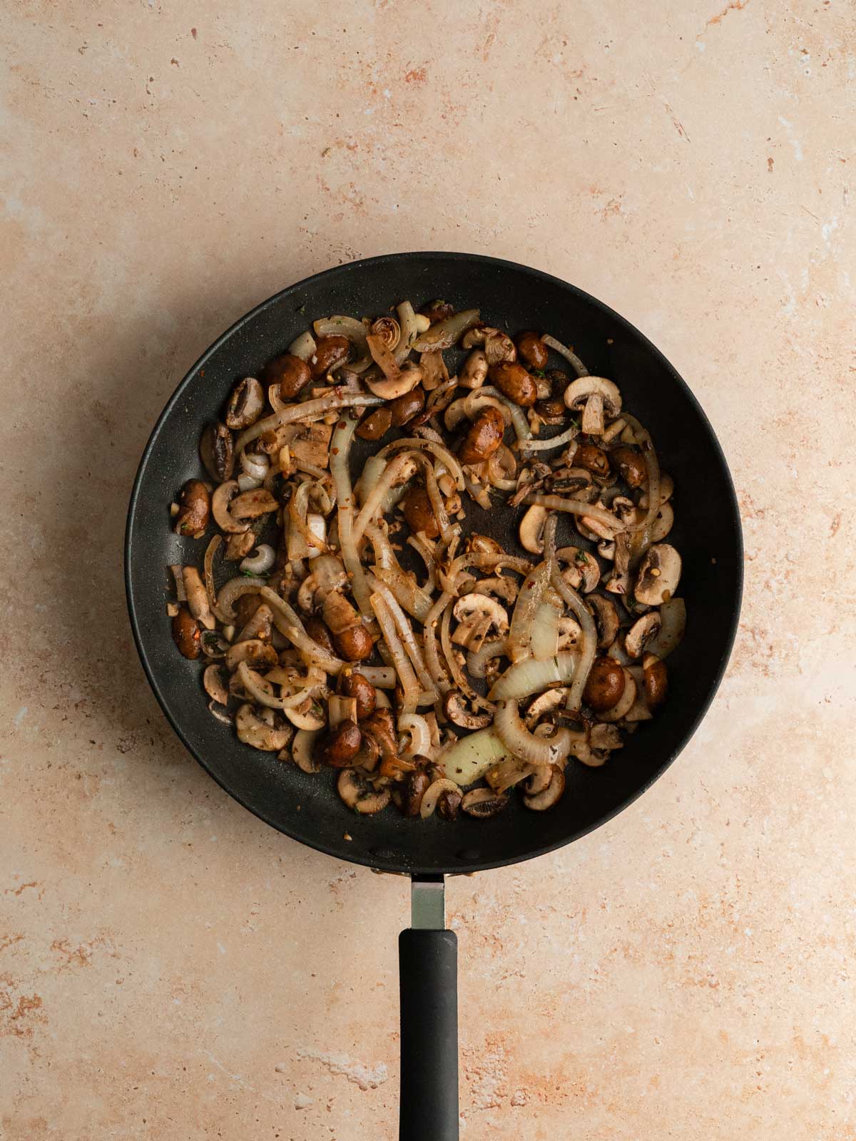 Mushrooms and seasoning cooking with the onions and garlic in a pan.