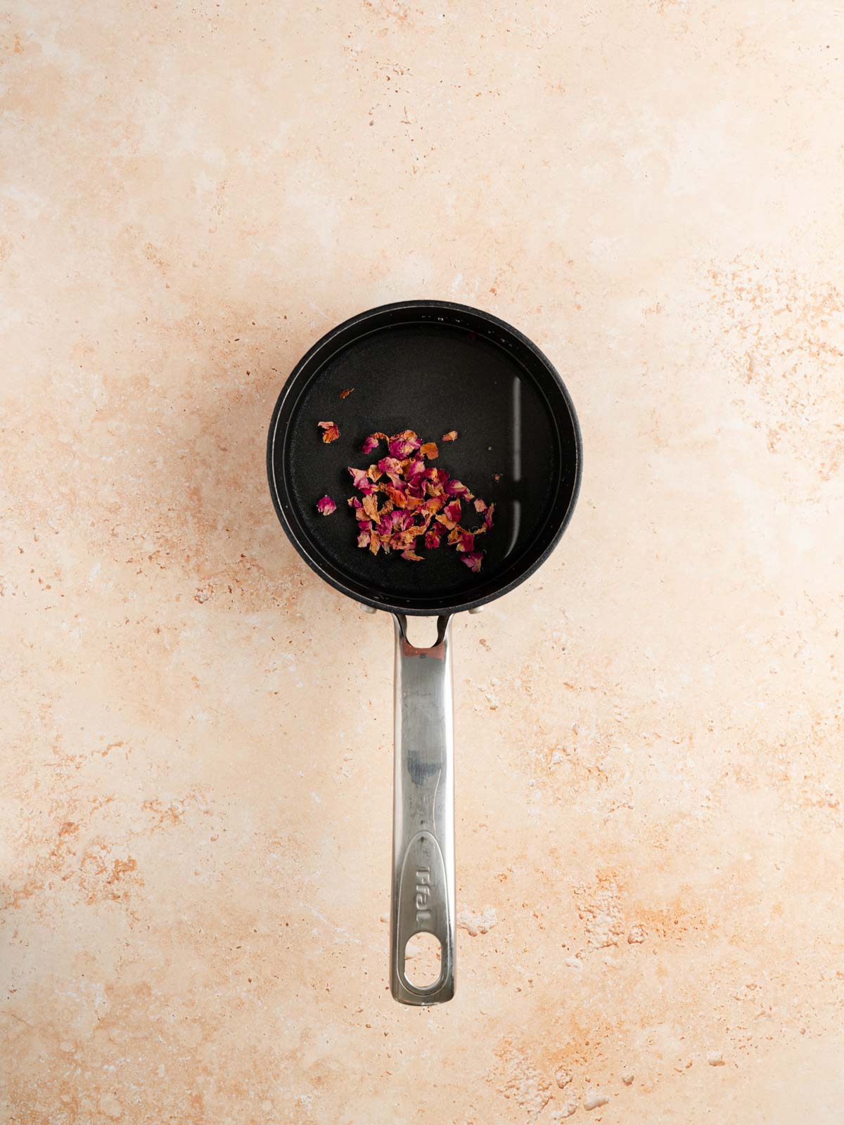 A pan with sugar, water and dried rose petals.