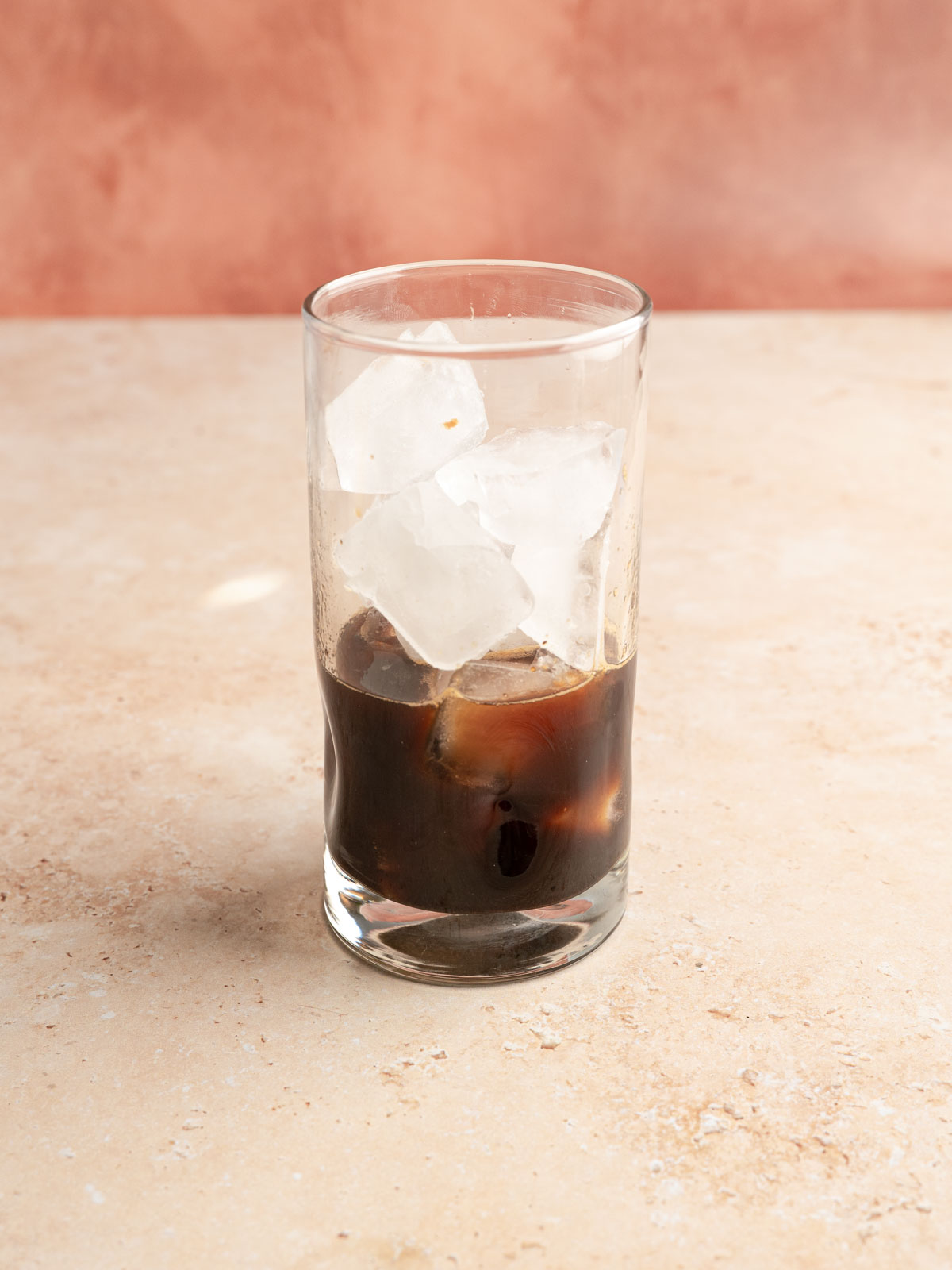 Ice added to a glass of rose cardamom infused espresso.