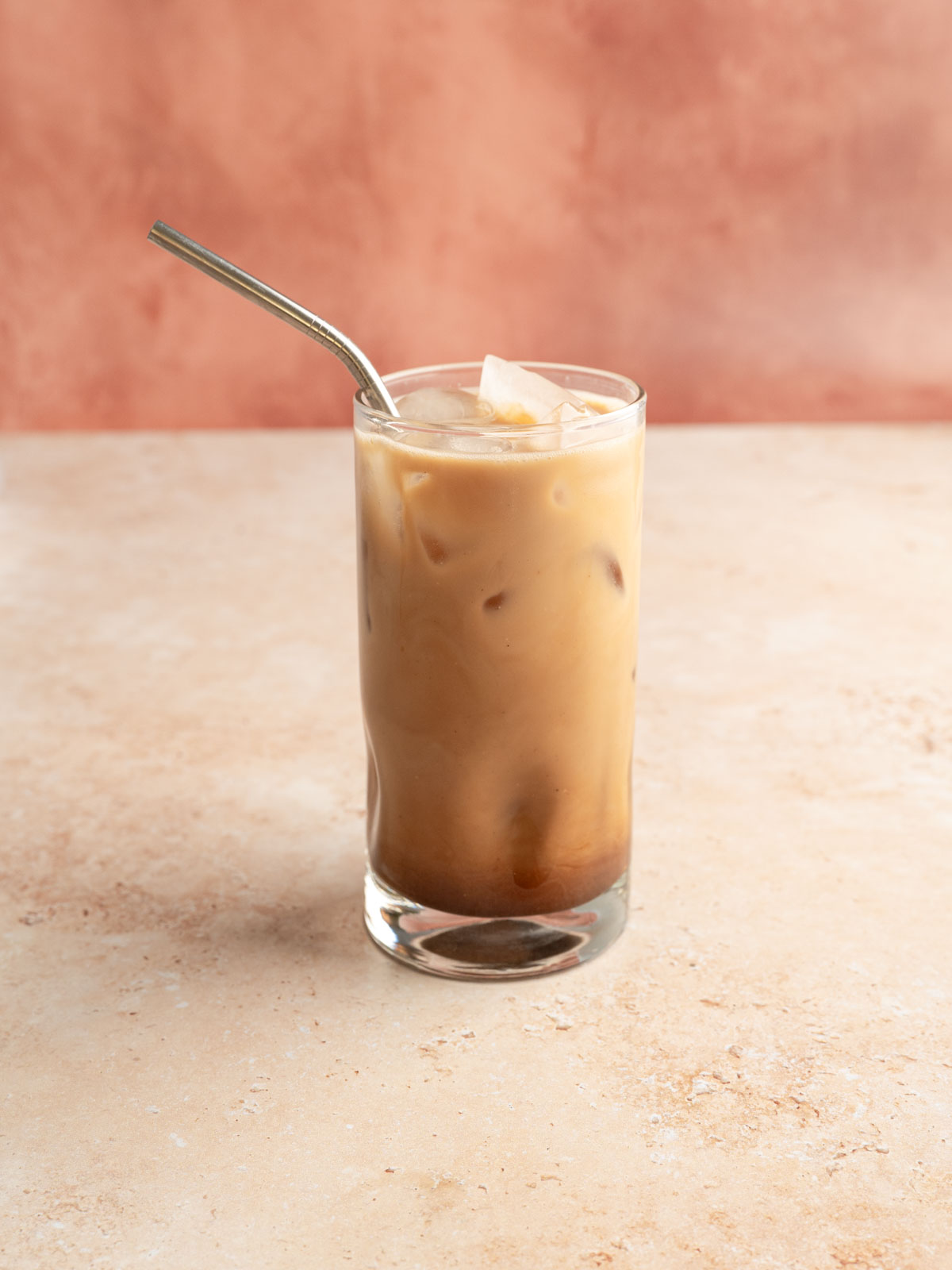 A rose cardamom latte served in a glass.