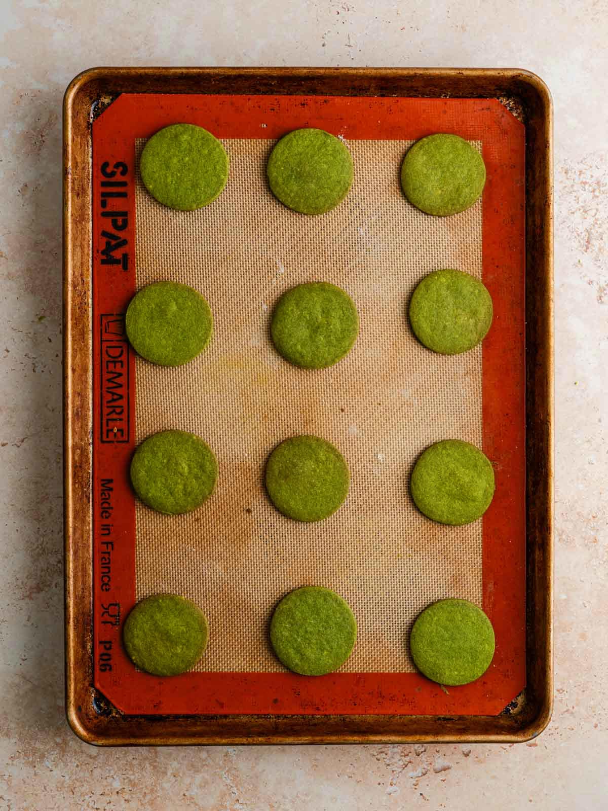 Baked matcha cookies on a baking sheet.