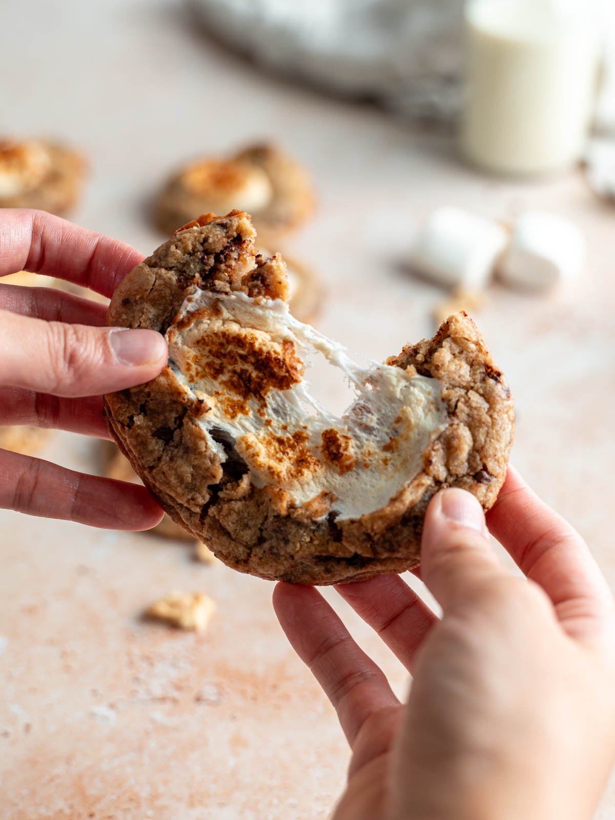 Vegan s'mores cookie slightly broken in half revealing the gooey marshmallow center.