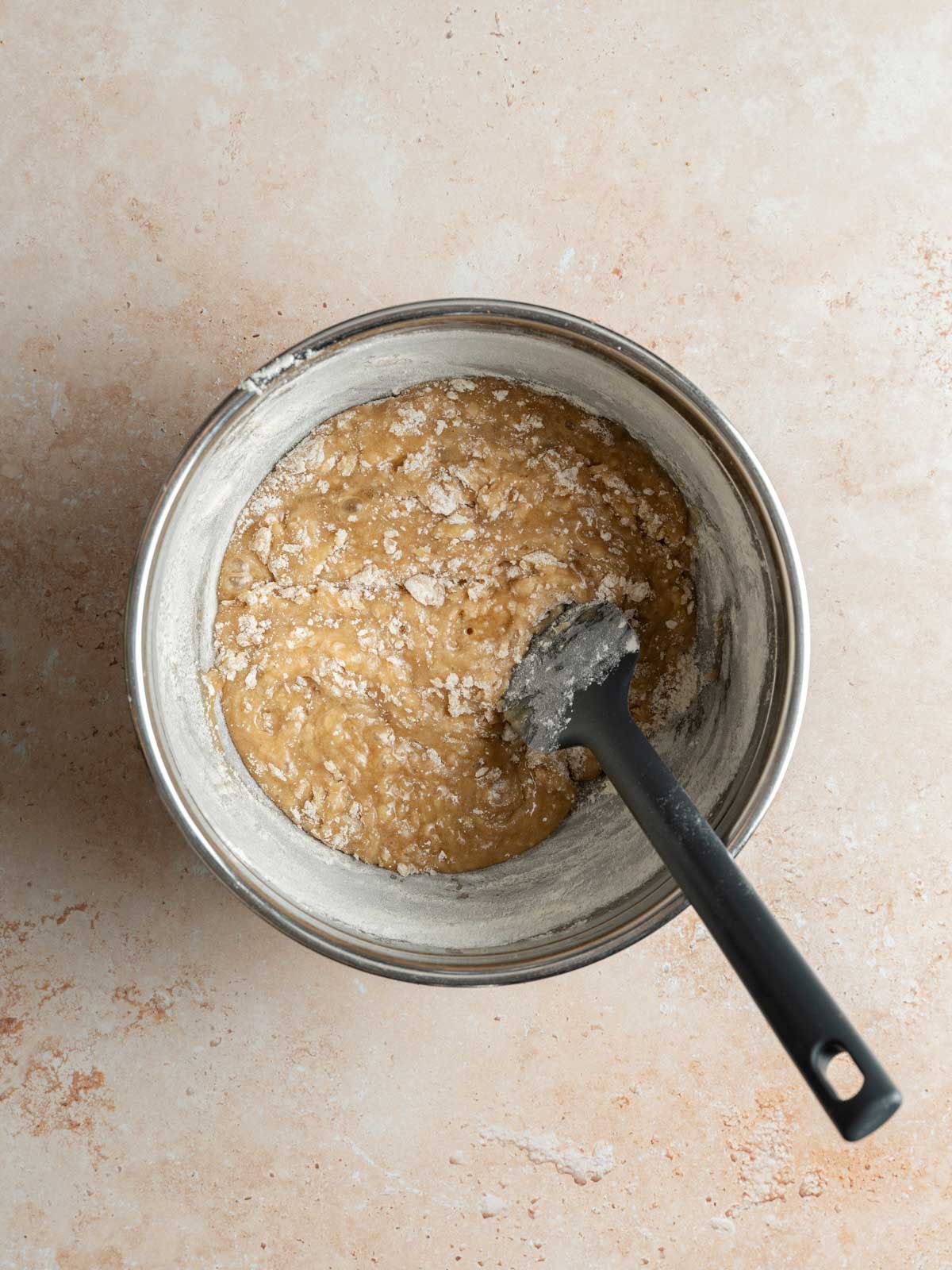 Combining the dry and wet ingredients to form the base of the cookie dough.