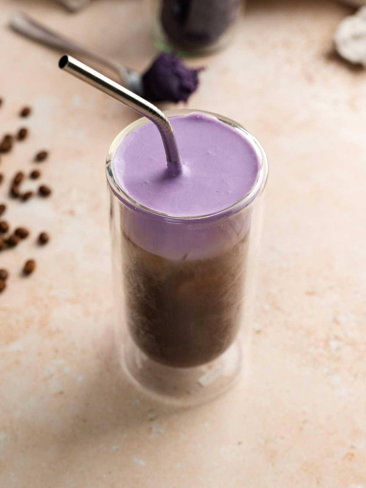 Tall glass of vegan ube cream cold brew with a straw.