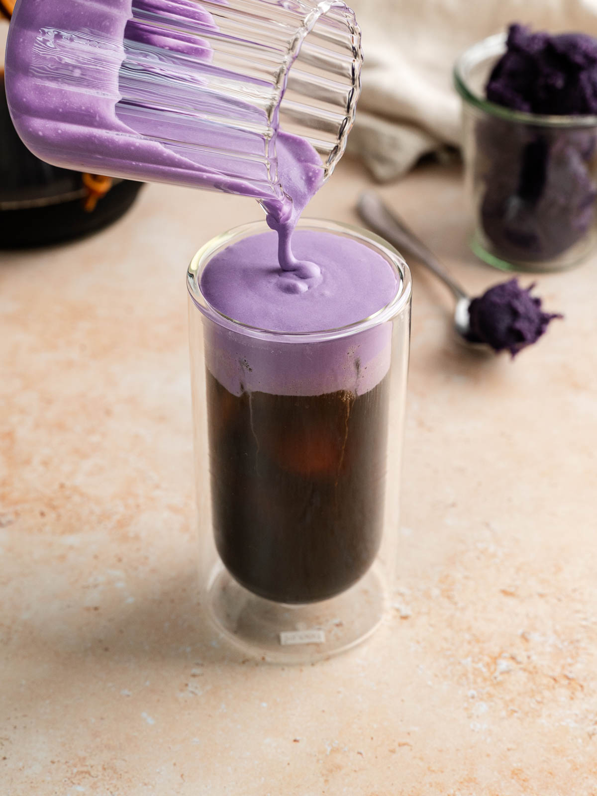 Ube cold foam pouring over top iced cold brew coffee.