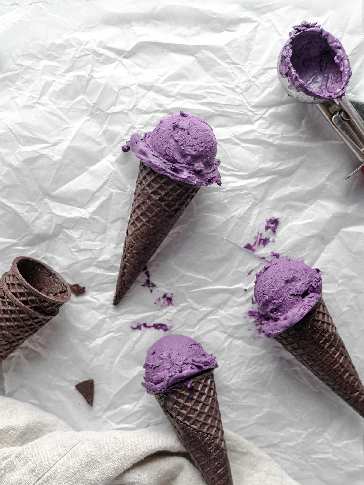 Three vegan ice cream cones laid on top of parchment paper.