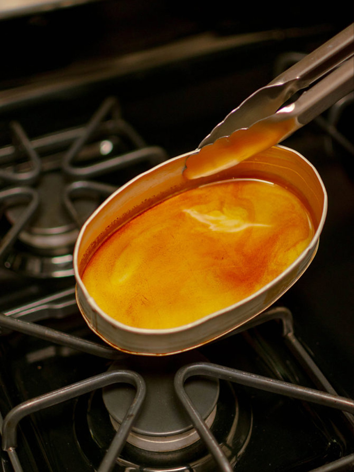 Sugar turned into a caramel in a llanera set over a stovetop.