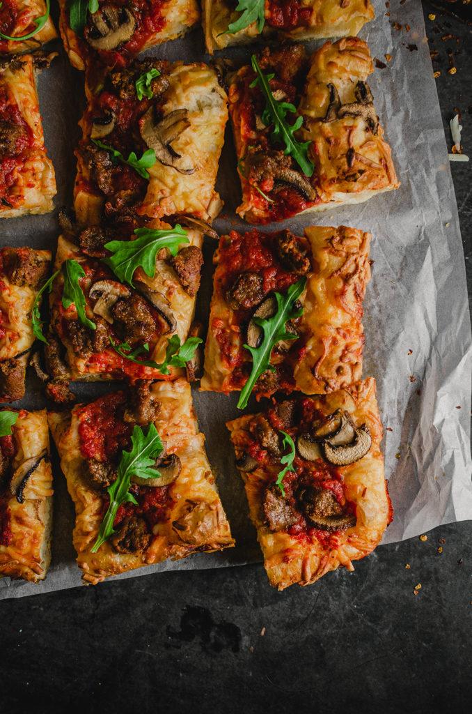 Top view of the vegan Detroit-style pizza, cut into twelve squares, set on top of a piece of parchment paper.