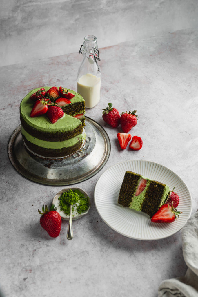 45 degree angle a slice of vegan matcha strawberry cake and the rest of the cake next to it