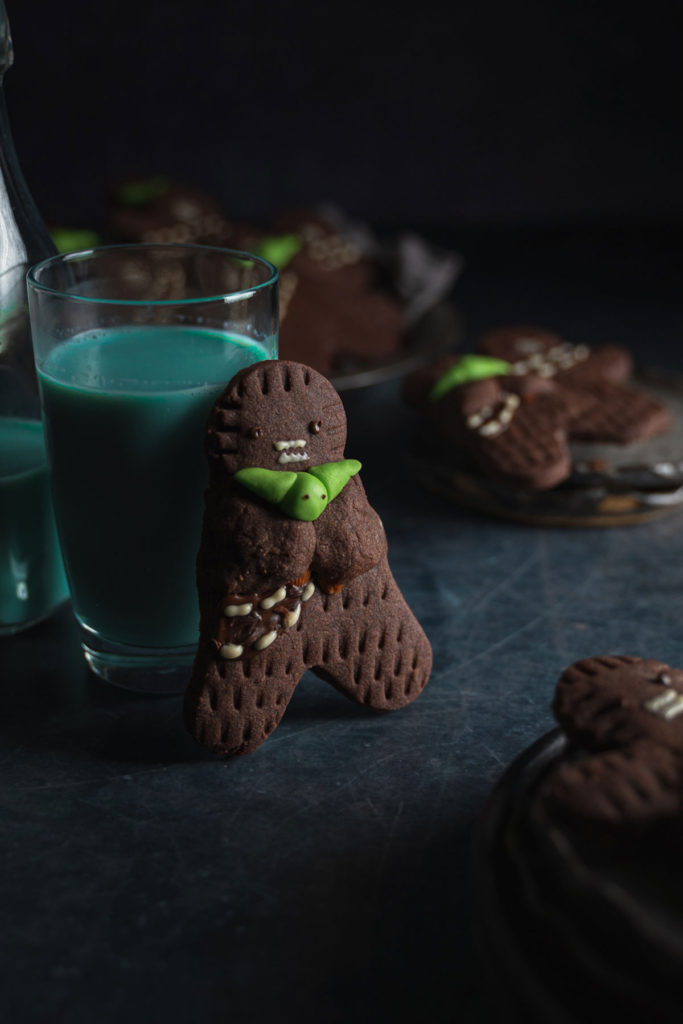 One wookie cookie, holding yoda, and standing next to a glass of blue milk.