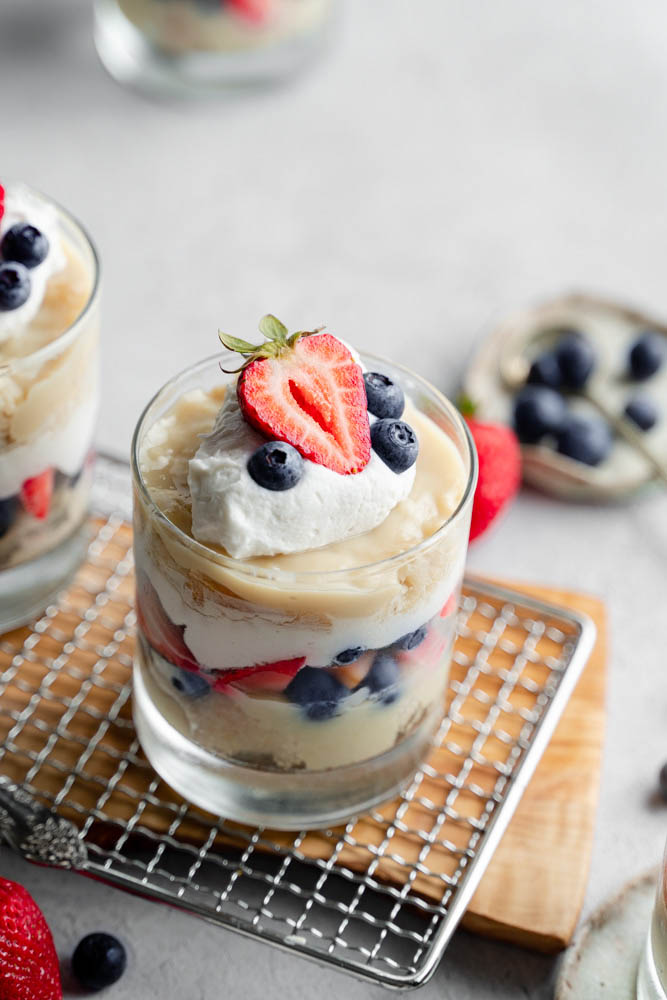 A single of a vegan berry trifle cup, blueberries in the back and out of focus.