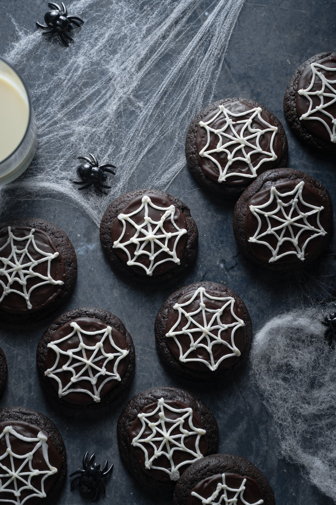 Top view vegan halloween spooky cookies laid over a surface with fake cobwebs surrounding it.