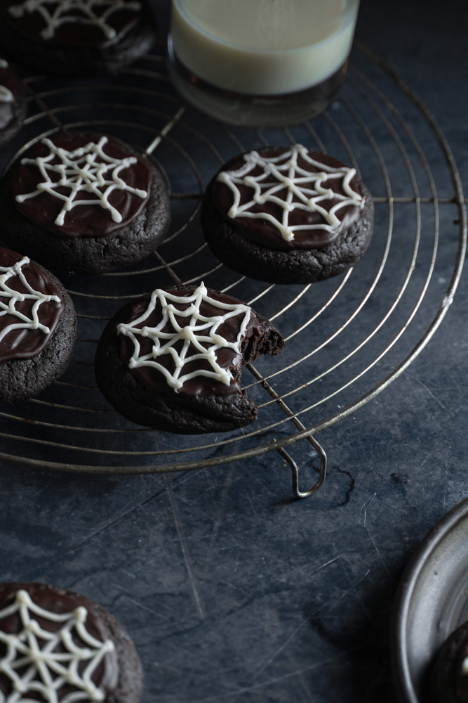 45 degree angle of vegan spooky cookies on a circle wire rack, and one taken a bite out of it. 