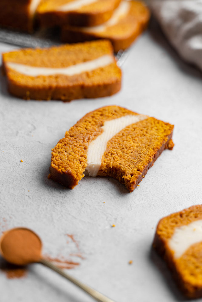 A slice of vegan pumpkin cheesecake bread with a bite taken out of it.