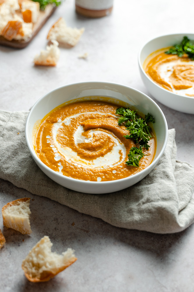 A bowl of vegan savory pumpkin soup, set on top of a napkin. 