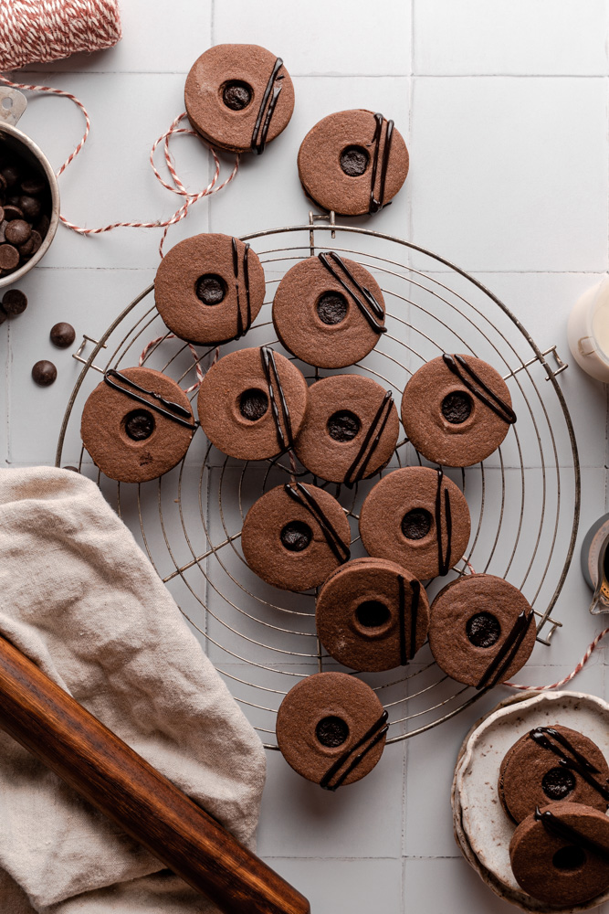 Vegan chocolate sandwich cookies on top of a round wire rack.