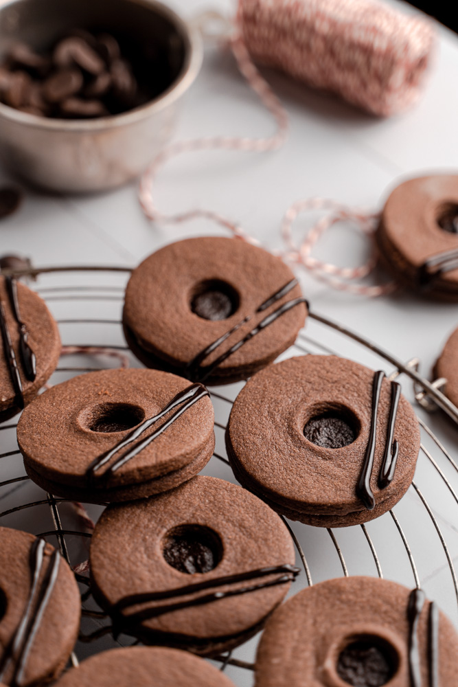 Vegan chocolate sandwich cookies on top of a round wire rack.
