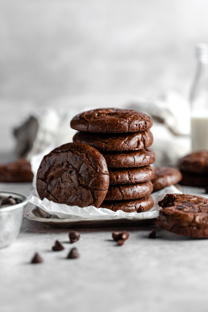 A stack of fudgy brownie cookies with one sitting next to it.