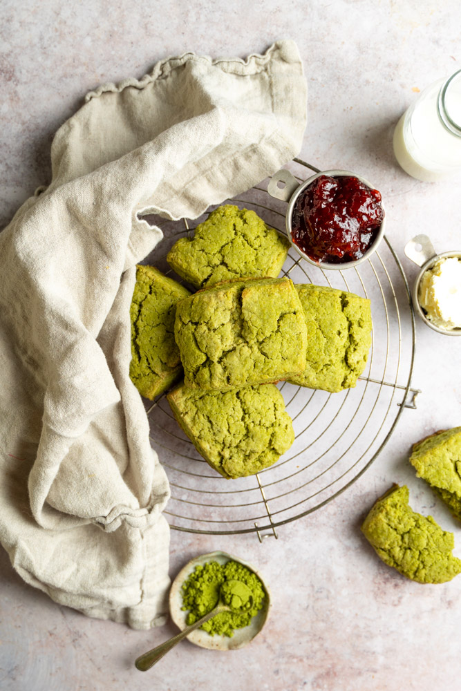 vegan matcha scones stacked on top of a round cooling rack.