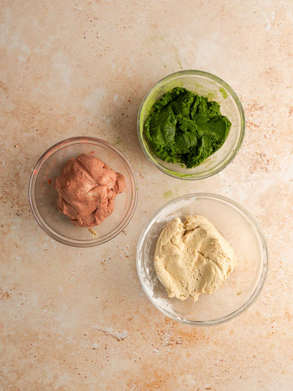 Three separate cookie doughs with a strawberry flavor, matcha flavor, and vanilla.