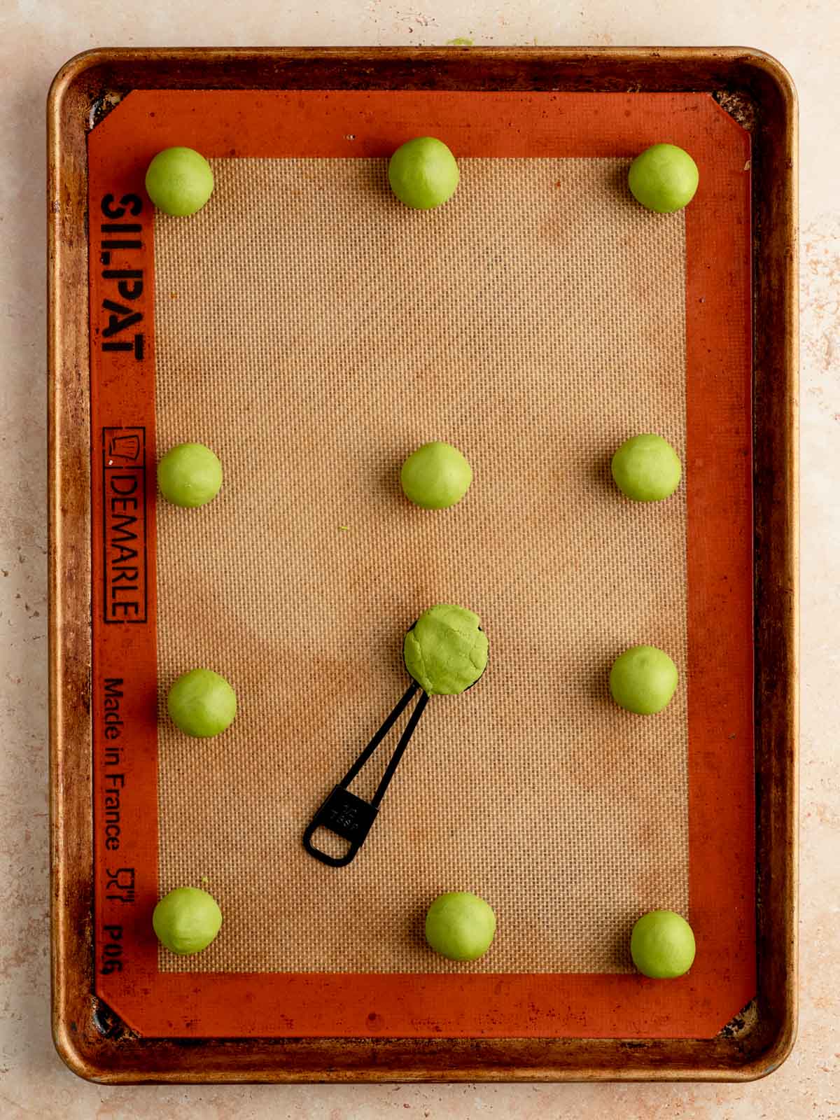 Matcha cookie dough scooped and rolled into balls on a baking sheet.